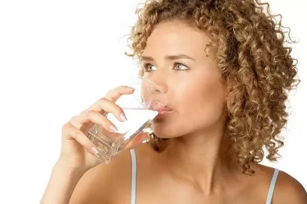 The girl follows a diet to be lazy, drinking a glass of water before eating